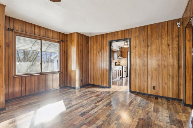 unfurnished room with dark wood-type flooring, ceiling fan, and wooden walls