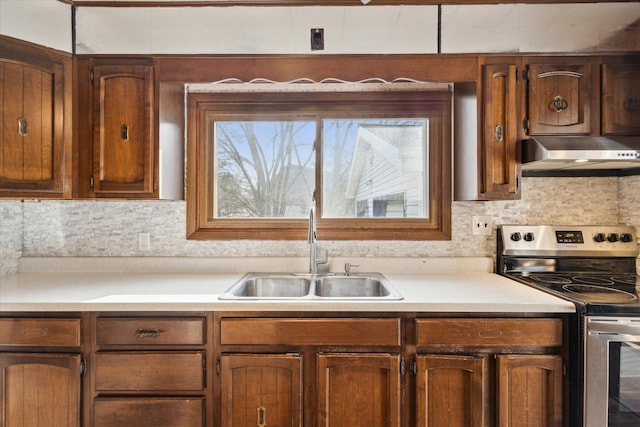 kitchen featuring sink, decorative backsplash, and stainless steel range with electric cooktop