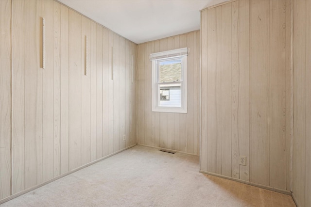 empty room with light colored carpet and wood walls