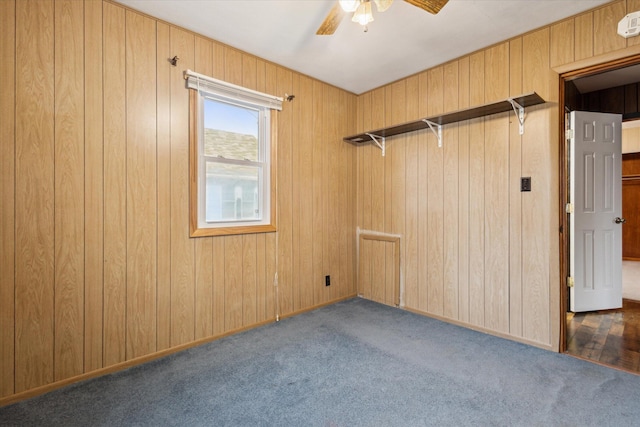 carpeted spare room with ceiling fan and wood walls