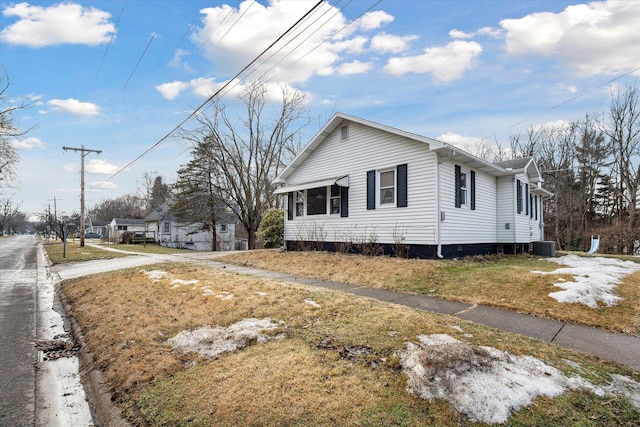 view of side of property featuring central AC and a lawn