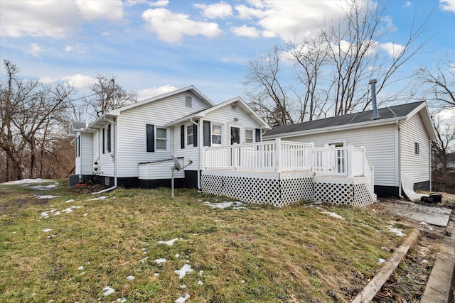 rear view of house featuring central AC, a deck, and a lawn