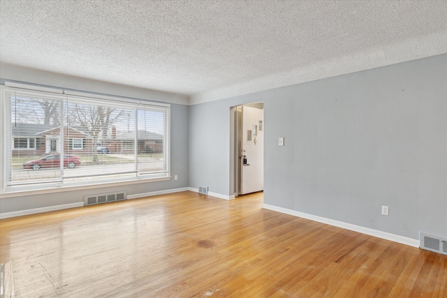 unfurnished room featuring light hardwood / wood-style flooring and a textured ceiling