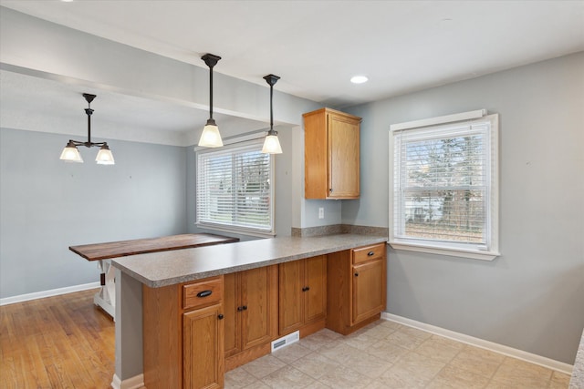 kitchen with a healthy amount of sunlight, decorative light fixtures, and kitchen peninsula