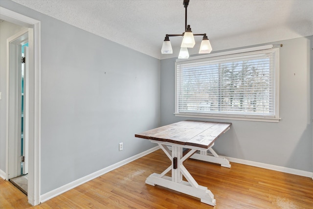 dining space with hardwood / wood-style floors and a textured ceiling