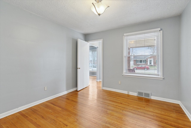 spare room featuring light hardwood / wood-style floors and a textured ceiling