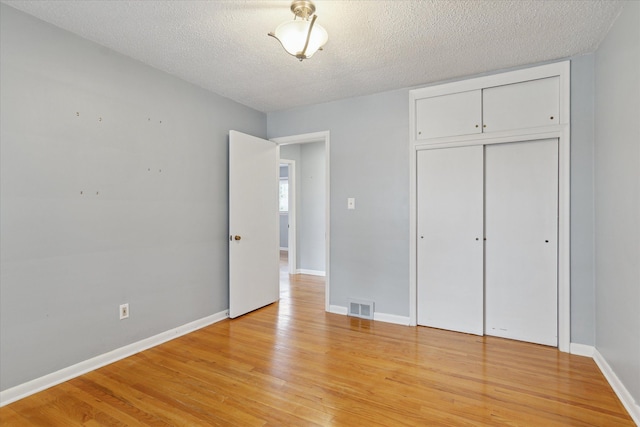 unfurnished bedroom with a closet, a textured ceiling, and light wood-type flooring