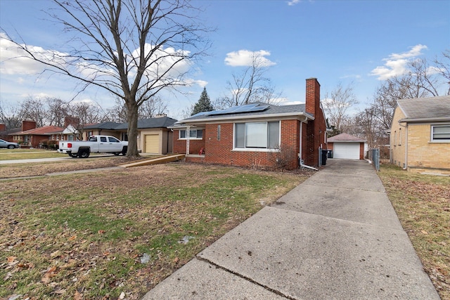 view of front of property featuring an outbuilding, a garage, a front yard, and solar panels