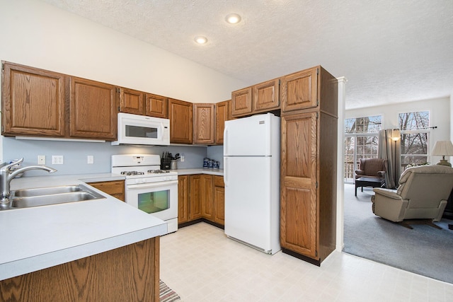 kitchen with sink, white appliances, high vaulted ceiling, and a textured ceiling