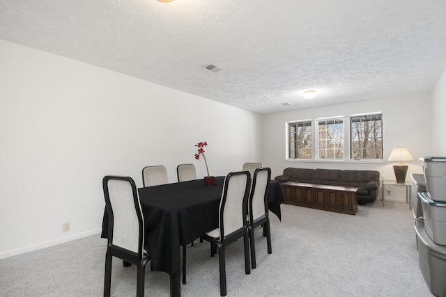 dining space with light colored carpet and a textured ceiling