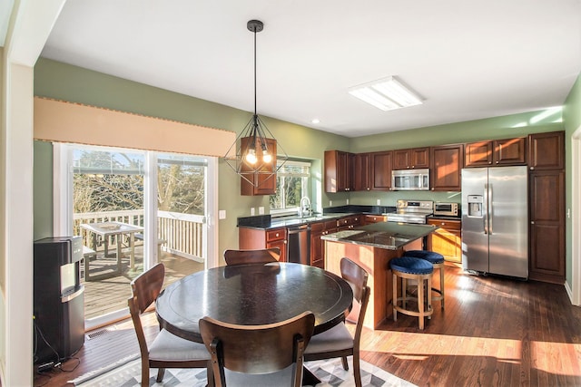 kitchen featuring sink, appliances with stainless steel finishes, dark hardwood / wood-style floors, a kitchen island, and pendant lighting