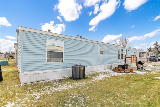 back of property featuring a lawn and central air condition unit