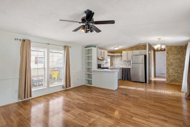 kitchen with hanging light fixtures, stainless steel fridge, and light hardwood / wood-style flooring