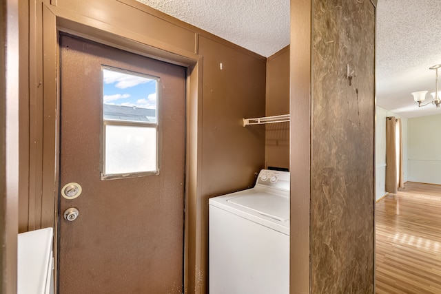 laundry room featuring hardwood / wood-style flooring, washer / dryer, a textured ceiling, and a notable chandelier