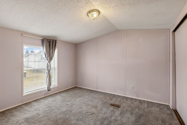 unfurnished room with carpet floors, a textured ceiling, and vaulted ceiling