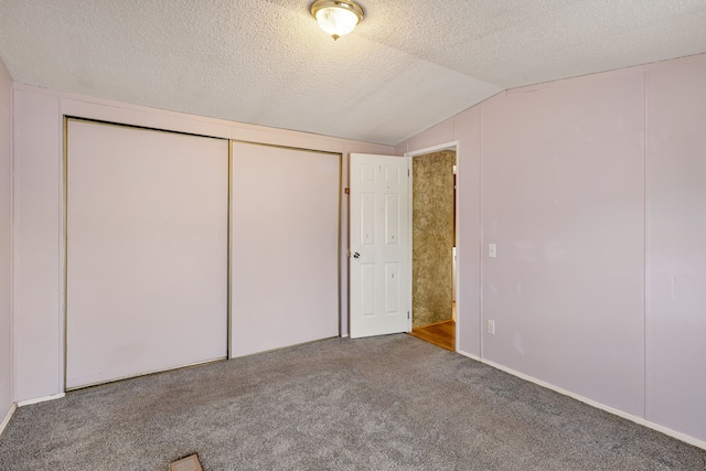 unfurnished bedroom with lofted ceiling, carpet flooring, a textured ceiling, and a closet