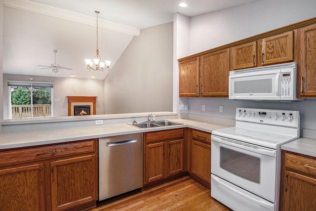 kitchen with vaulted ceiling, decorative light fixtures, sink, kitchen peninsula, and white appliances