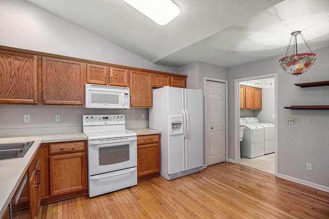 kitchen featuring lofted ceiling, white appliances, hanging light fixtures, washer and dryer, and light wood-type flooring