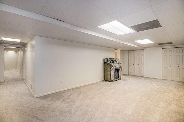 basement featuring a paneled ceiling and light colored carpet