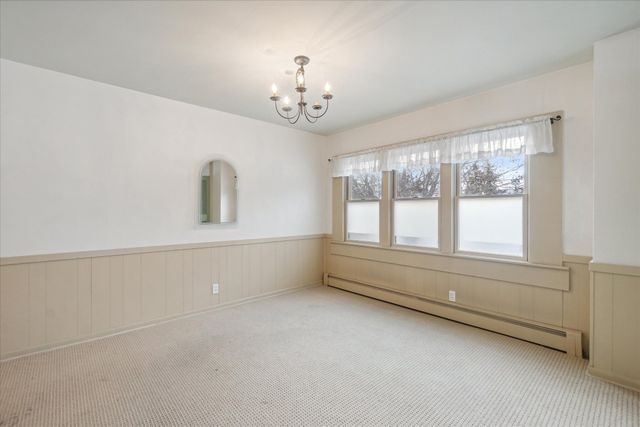 spare room with a baseboard heating unit, light colored carpet, and a chandelier