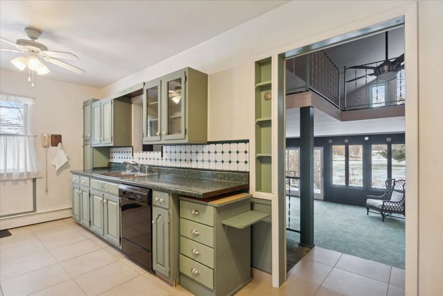 kitchen with dishwasher, sink, backsplash, green cabinets, and light tile patterned floors