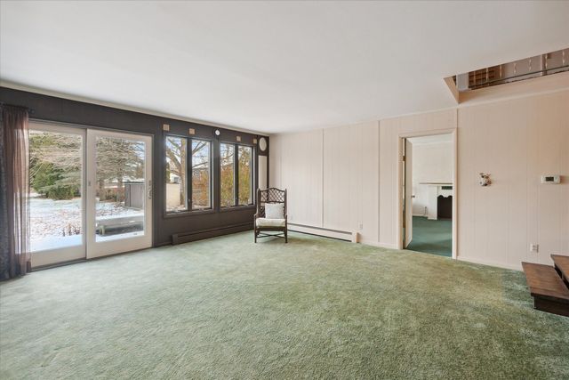 interior space with a baseboard radiator, a healthy amount of sunlight, and carpet flooring