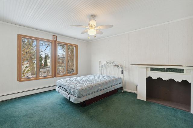 bedroom featuring ornamental molding, a baseboard heating unit, ceiling fan, and dark carpet