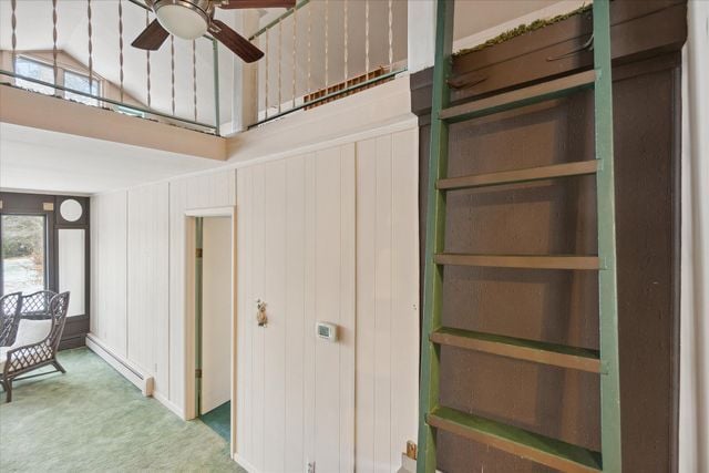 interior space with a baseboard heating unit, vaulted ceiling, ceiling fan, and carpet