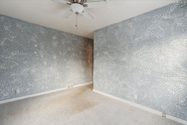 unfurnished room with ceiling fan and carpet