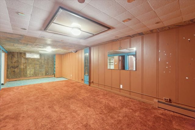 basement with carpet flooring and a baseboard heating unit