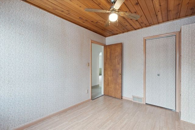 unfurnished bedroom with wood ceiling, light hardwood / wood-style floors, a closet, and ceiling fan