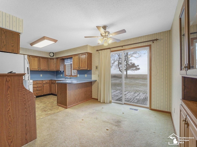 kitchen with white fridge, light colored carpet, ceiling fan, kitchen peninsula, and a textured ceiling