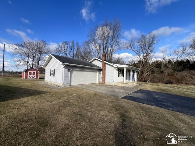 view of front facade with a garage, a storage shed, covered porch, and a front lawn