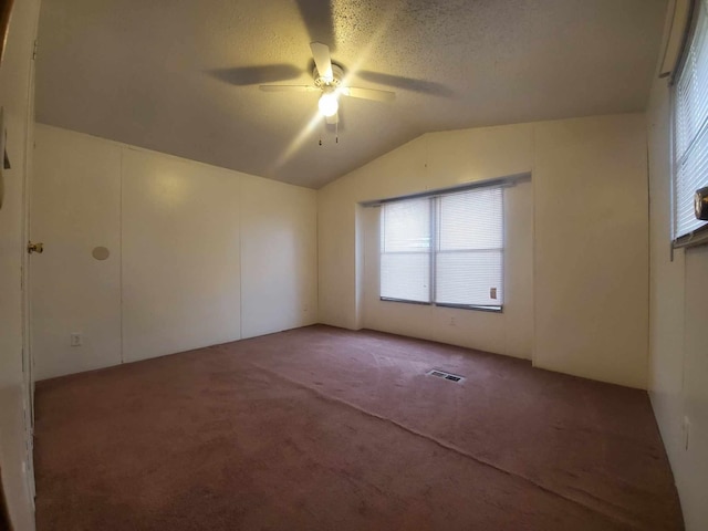 spare room featuring carpet floors, ceiling fan, vaulted ceiling, and a textured ceiling