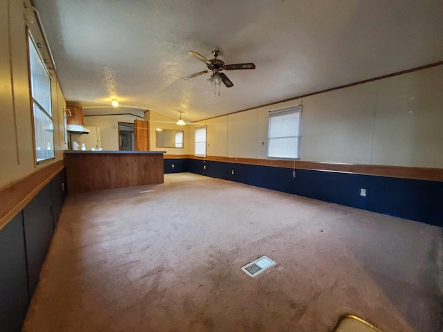 unfurnished living room with lofted ceiling, ceiling fan, and carpet flooring