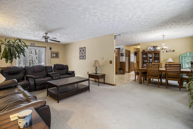 living room featuring ceiling fan with notable chandelier, light carpet, and a textured ceiling