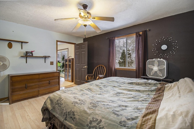 bedroom with ceiling fan, a textured ceiling, and light hardwood / wood-style floors