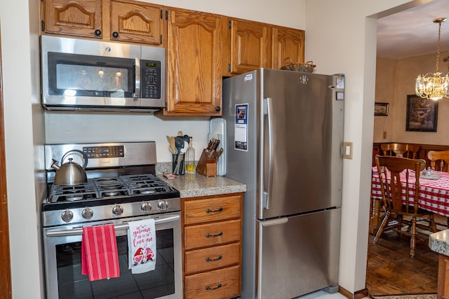 kitchen featuring stainless steel appliances, pendant lighting, and a notable chandelier