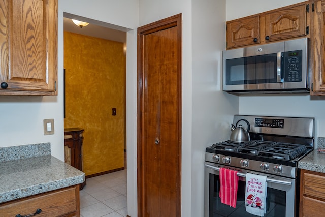 kitchen with light stone countertops, stainless steel appliances, and light tile patterned flooring