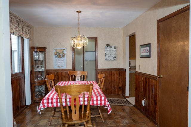 dining room featuring dark parquet flooring, a notable chandelier, and wood walls