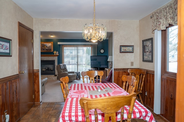 dining space with a notable chandelier, dark parquet floors, and wood walls