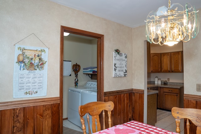 tiled dining space with washer and clothes dryer and wood walls