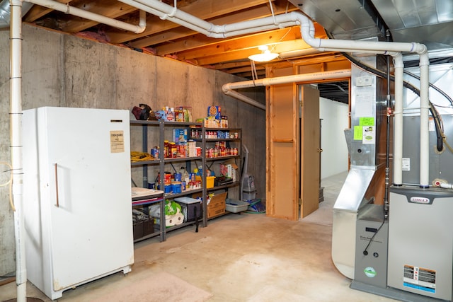 basement featuring white refrigerator and heating unit