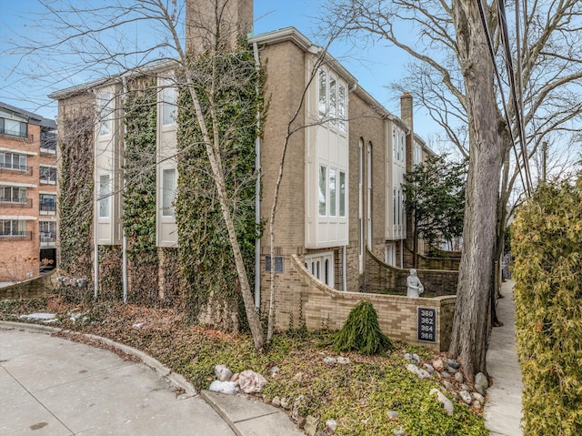 view of side of property with a chimney and brick siding