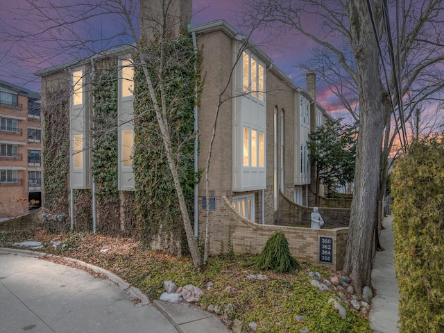 property exterior at dusk featuring brick siding