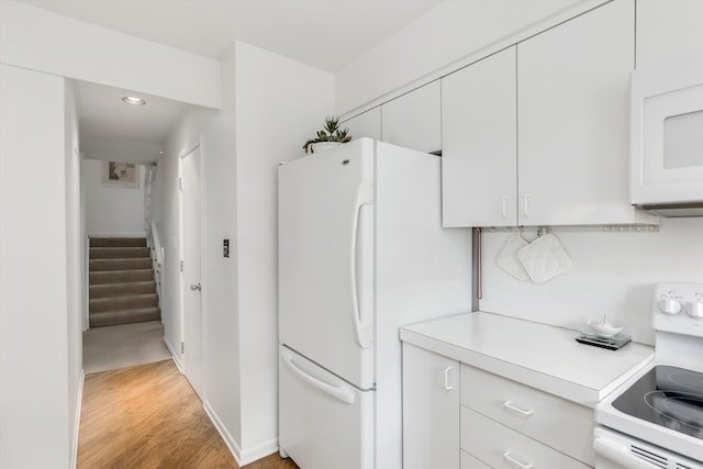 kitchen with white cabinets, white appliances, and light hardwood / wood-style flooring