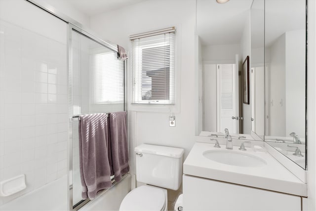 bathroom featuring toilet, enclosed tub / shower combo, and vanity