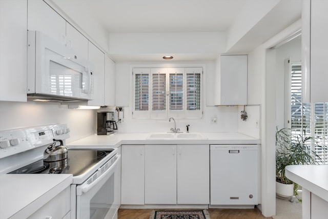 kitchen with white cabinetry, white appliances, plenty of natural light, and sink