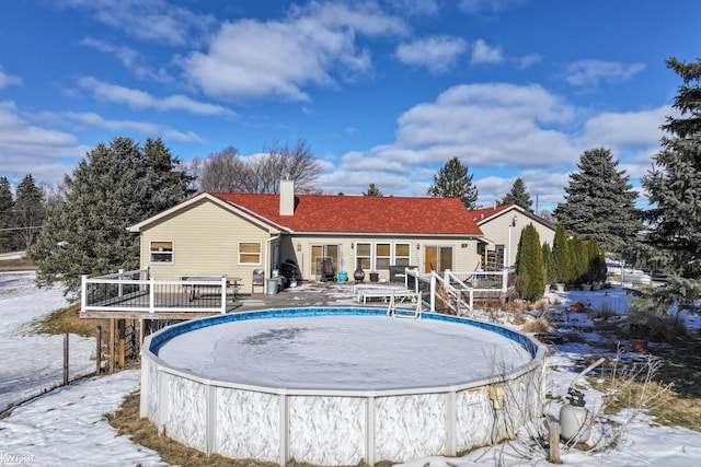 snow covered back of property with a swimming pool side deck