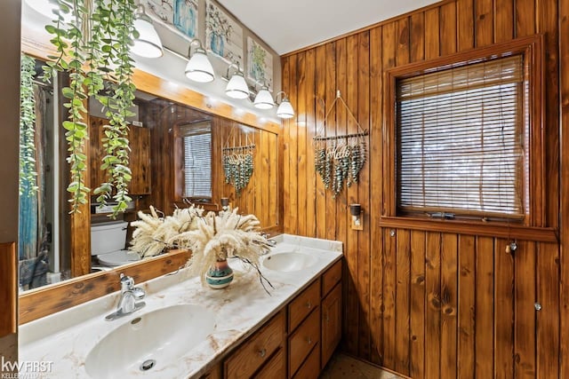 bathroom with wooden walls, vanity, and toilet